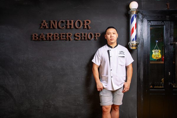 坐落九龍灣工廈的Anchor Barber Shop，門口以全黑色透灰的色調及復古字樣的店名作主題牆，呈現型格時尚風格。